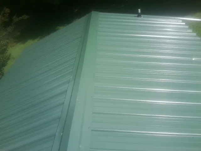 New green metal panels meeting at the ridge of a roof — Flat Roof Repair work by our crew in Hartwell