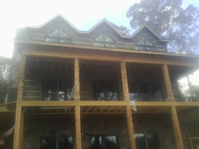Dormers and porch framing on a large log home under construction — Roof Coating work by our crew in Hartwell