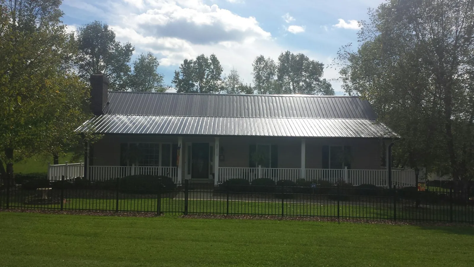 Gray metal roof on a brick ranch with a full width front porch — Gutter Guard Installation work by our crew in Hartwell