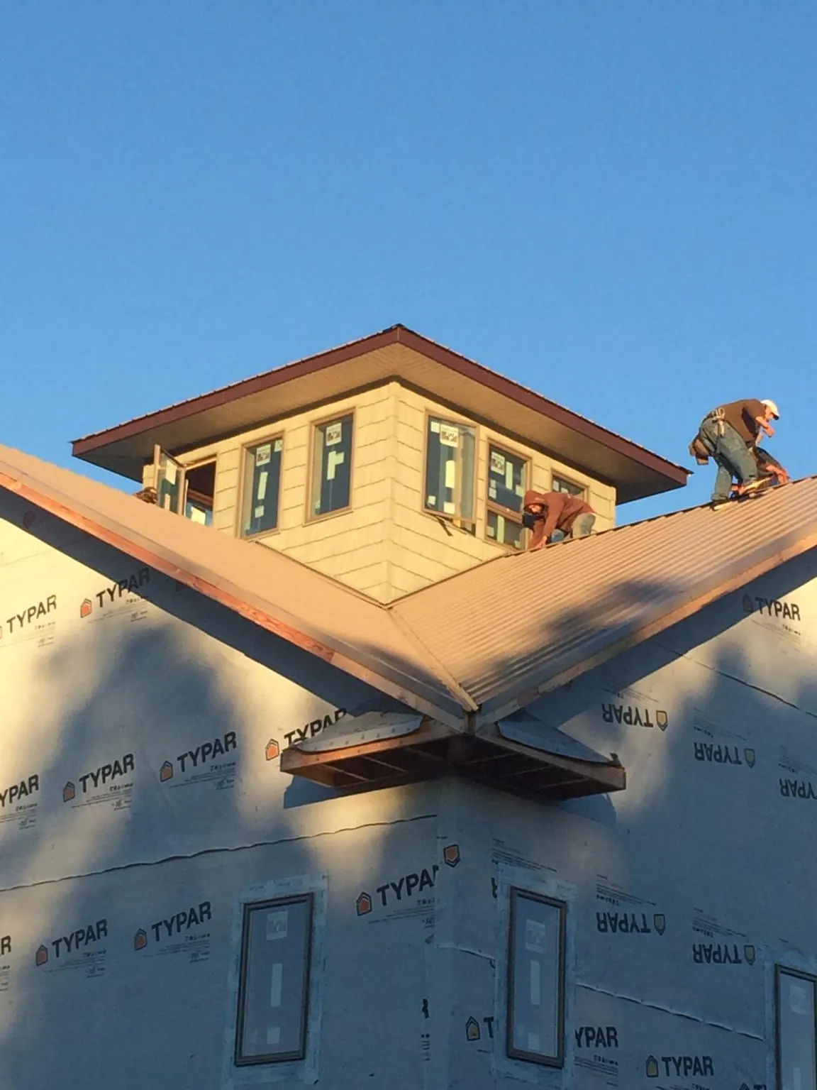 Roofers working around a rooftop cupola on a new metal roof at sunset — Roof Waterproofing in Hartwell by Roofing Brothers